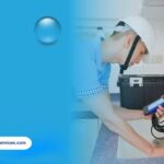 Professional plumber performing sewer camera inspection under kitchen sink to detect plumbing issues
